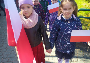 Dzieci z flagami przed budynkiem przedszkola